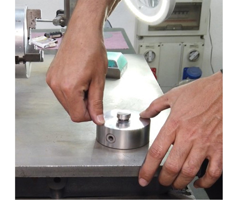 Checking the flatness of a load cell: the load cell is placed on a perfectly flat surface and the operator exerts a force on it with their fingers.