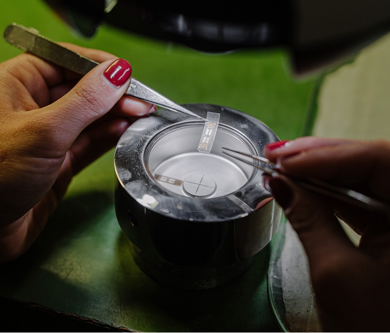 An operator lays the strain gauges precisely on the load cell in order to glue them.