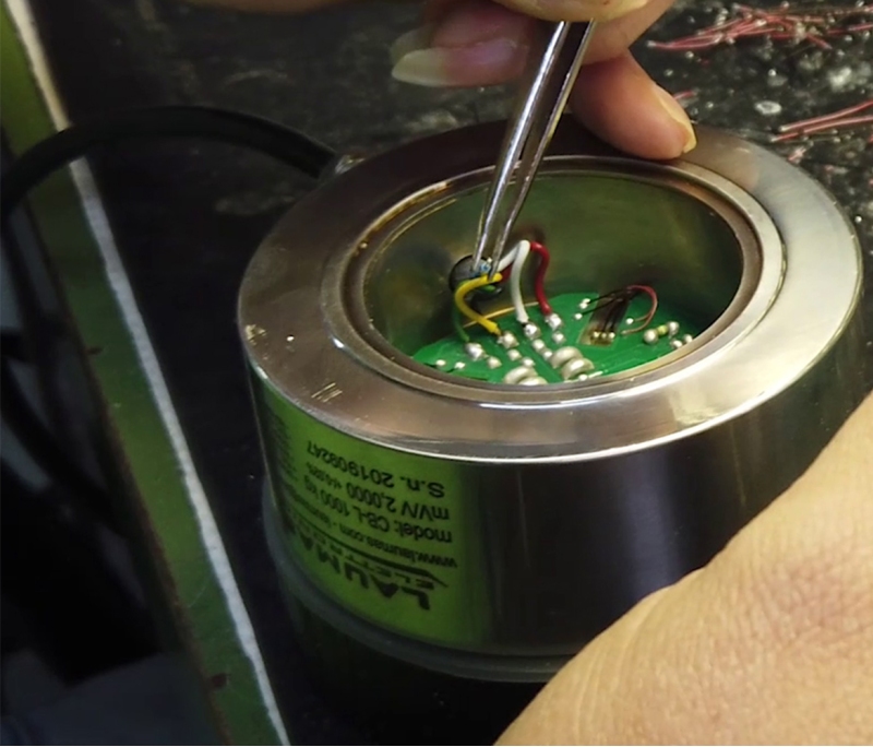 Wiring a load cell: an operator connects the electric wires to the PCB of the load cell and creates the Wheatstone bridge.